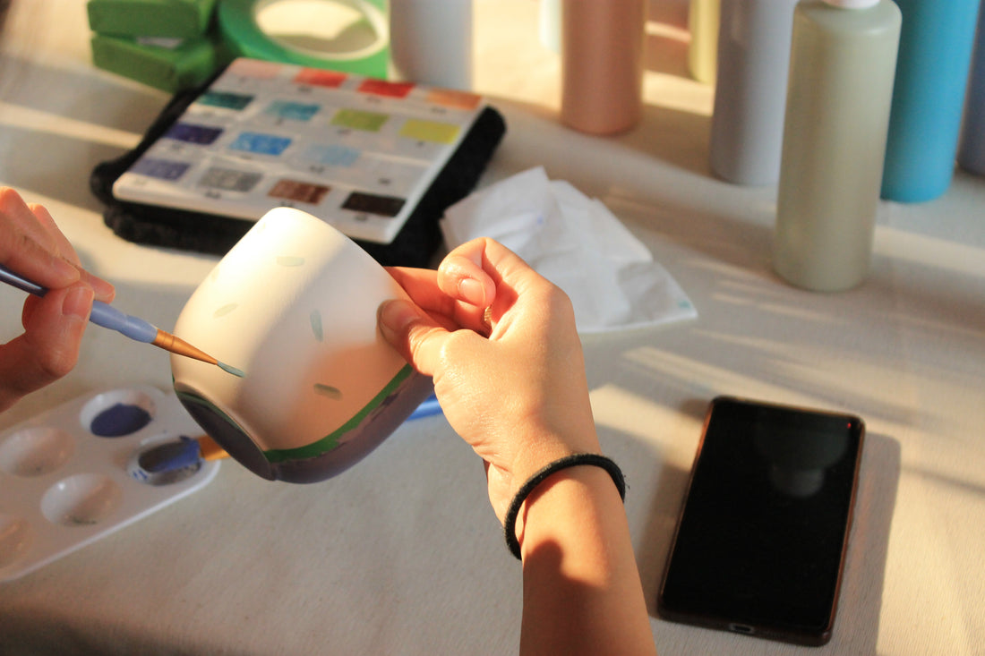 Image d'une personne entrain de peindre sur une pièce en céramique